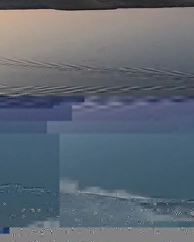 Glitched photograph of a seascape, broken into blocks of blue and grey.